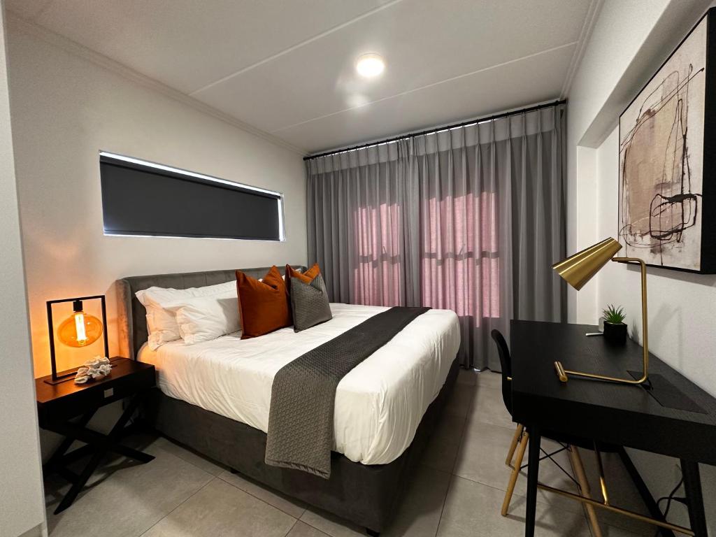 约翰内斯堡Stylish Executive Apartment with Power Backup的一间卧室配有一张床、一张书桌和一台电视