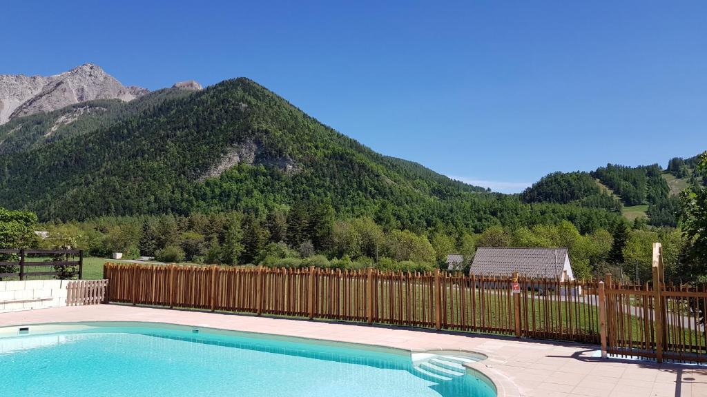 昂塞勒Camping les Auches的一座带围栏和山脉的游泳池