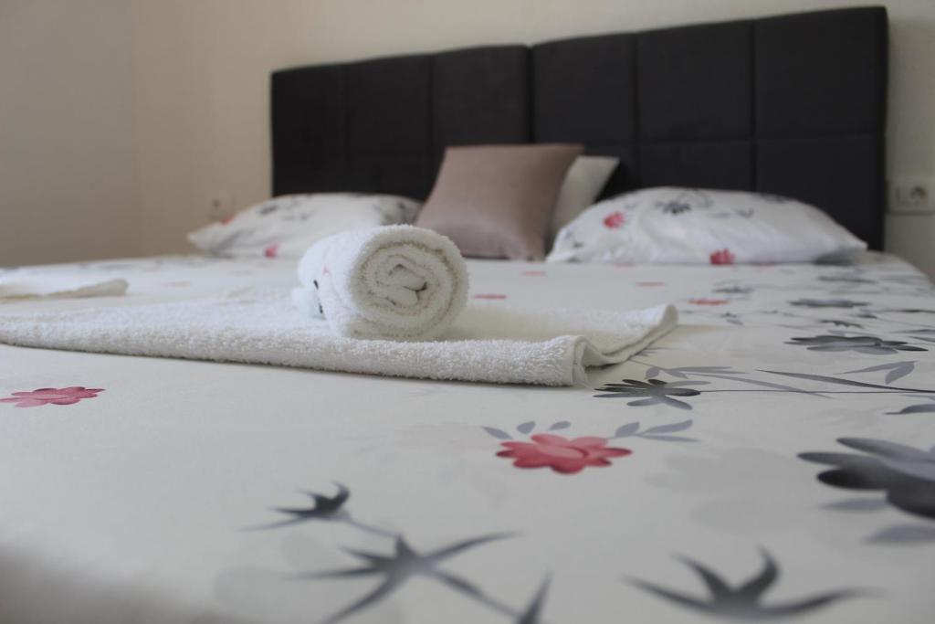 KomolacSun Studio Apartment的一张带毛巾和鲜花的白色床