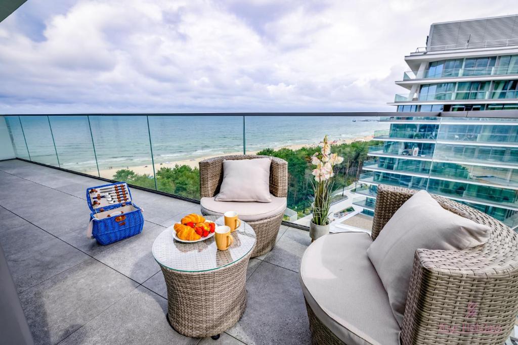 米兹多洛杰Your Holidays Waves A865的阳台配有桌椅,享有海景。