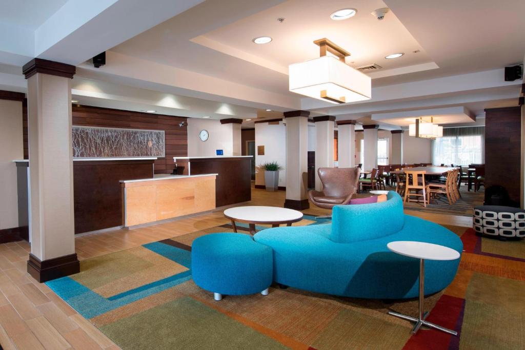 查尔斯顿北查尔斯顿/大学区费尔菲尔德套房酒店的大堂设有蓝色的沙发和桌椅