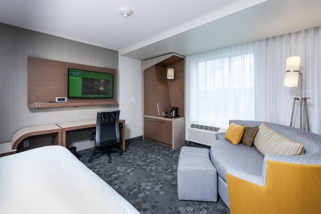 Littleton波士顿利特尔顿万怡酒店的酒店客房设有一张沙发和一张带电视的书桌。
