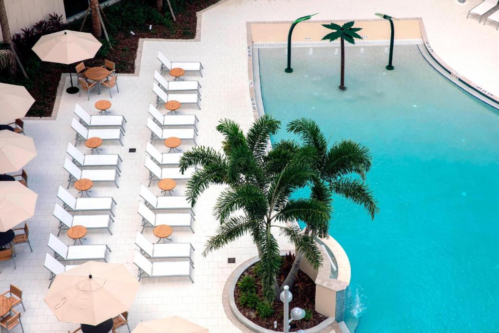 奥兰多TownePlace Suites by Marriott Orlando Theme Parks/Lake Buena Vista的享有带遮阳伞和棕榈树的游泳池的顶部景致