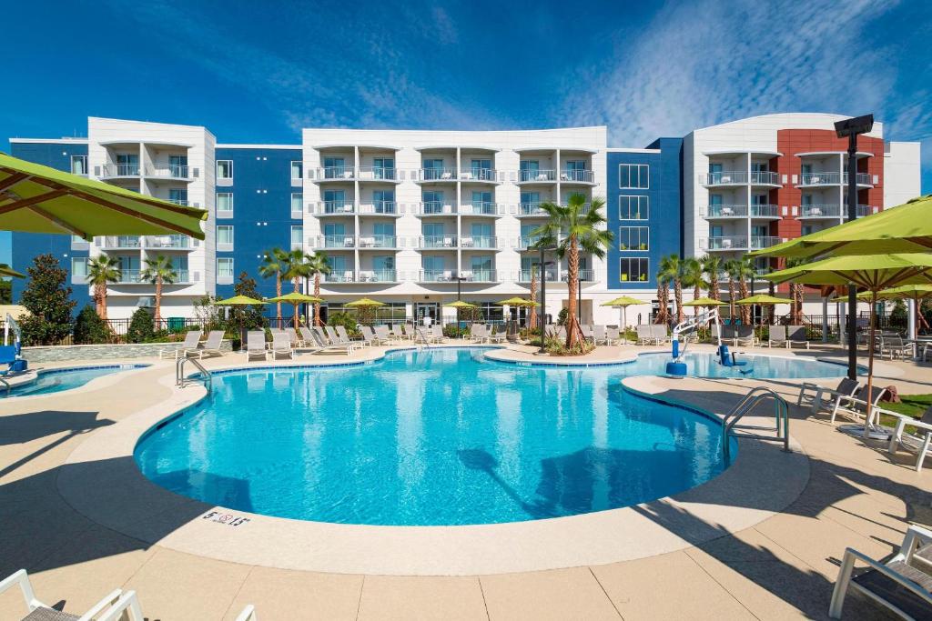 奥兰治比奇SpringHill Suites Orange Beach at The Wharf的酒店前方的游泳池配有椅子和遮阳伞