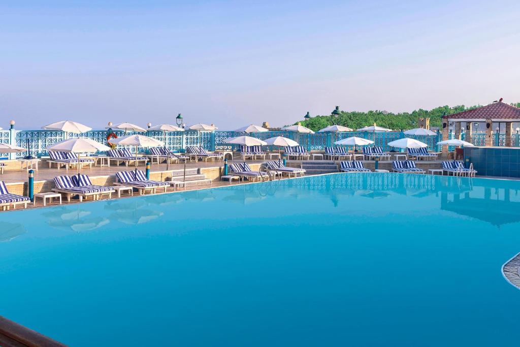 亚历山大蒙塔扎喜来登酒店的度假村的游泳池配有椅子和遮阳伞