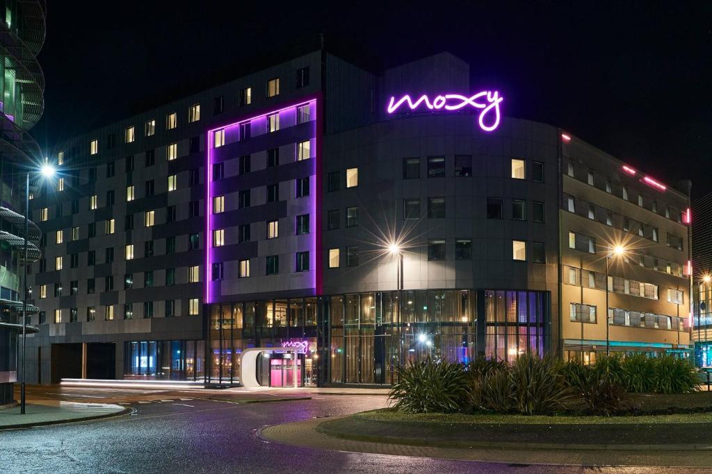 南安普敦Moxy Southampton的一座摩兹代纳建筑,上面有紫 ⁇ 虹灯标志