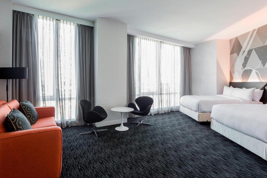 皇后区长岛市/纽约曼哈顿景观万怡酒店的酒店客房带两张床和一张桌子以及椅子。