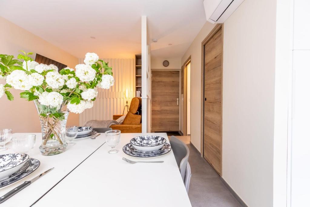 克莱蒙费朗At home in Clermont studio meublé Place de Jaude的用餐室配有带鲜花的白色桌子