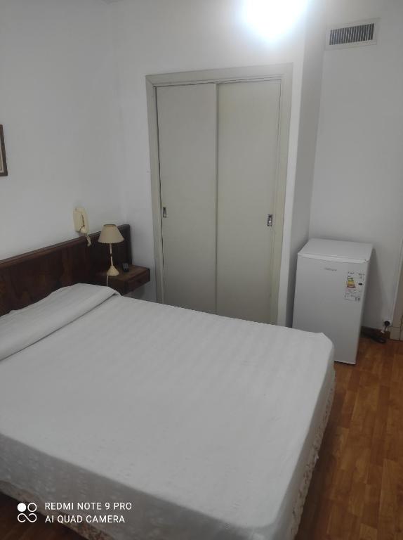 内科切阿Necochea Real Hotel的卧室配有白色的床和冰箱。