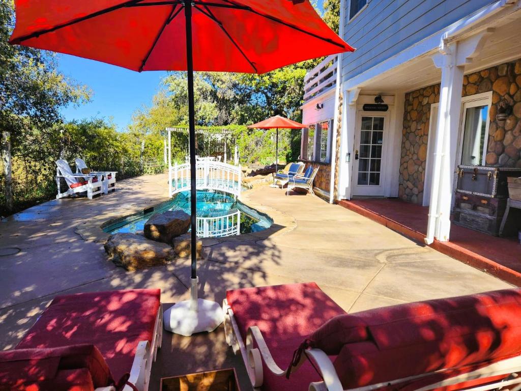 朱利安Oak Hill Inn的一个带红色遮阳伞和椅子的庭院和一个游泳池