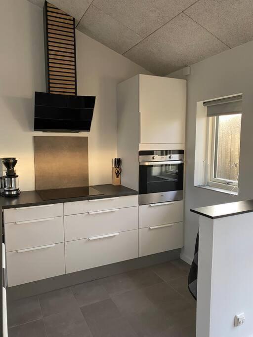 斯卡恩Fin ny moderniseret lejlighed i Skagen.的厨房配有白色橱柜和炉灶烤箱。