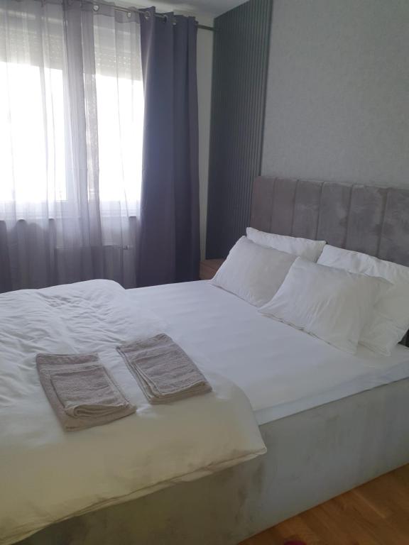 诺维萨德Sajam 1的一张带白色床单和枕头的床以及窗户