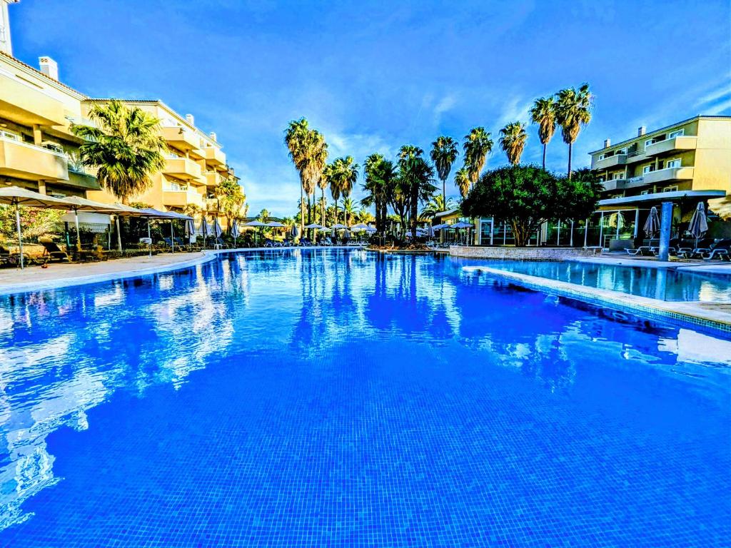 阿尔沃尔VilaBplaza by JohnVillas的一座拥有蓝色海水和棕榈树的大型游泳池