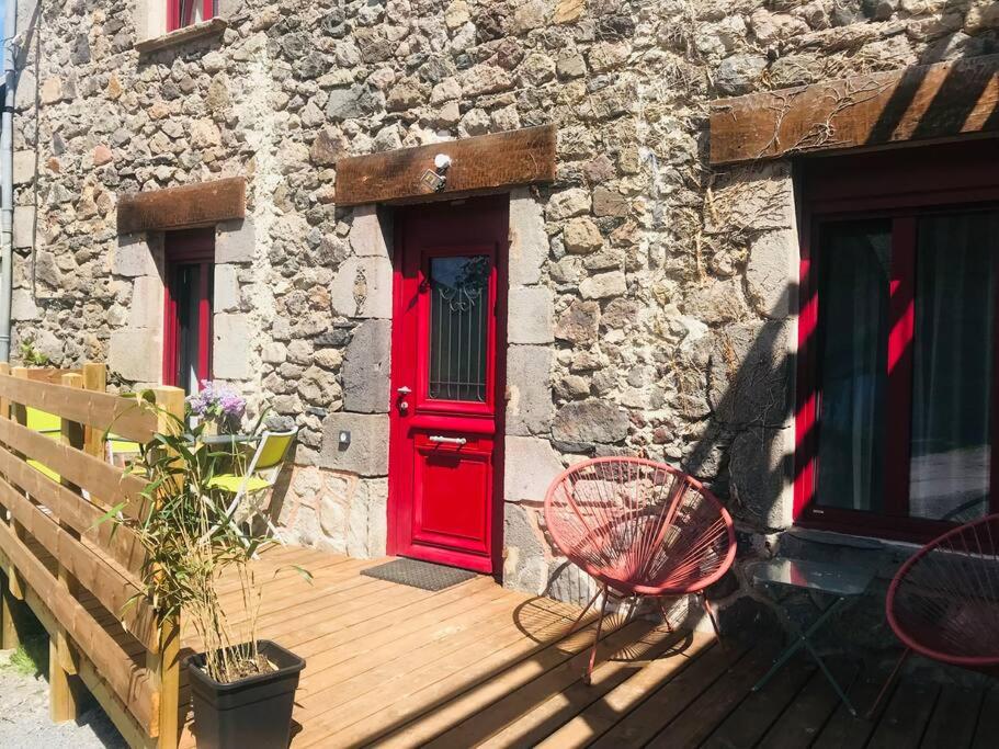 拉克河畔尚邦Chez Gaston的石头建筑的红色门,设有木甲板