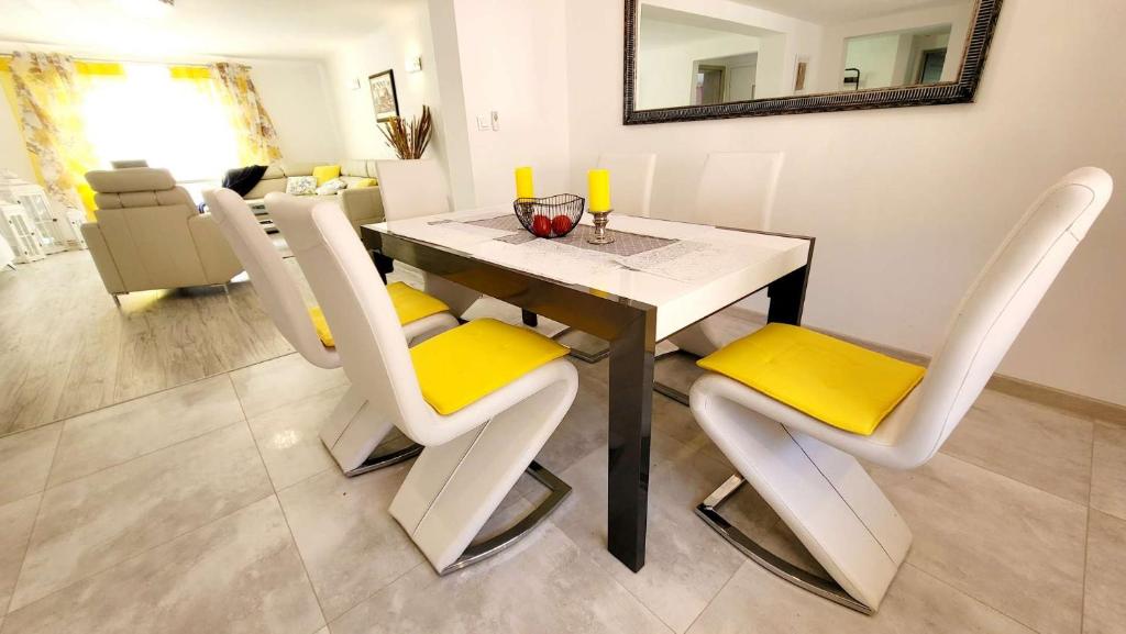 什切青Carpe Diem Lakeside Apartment的餐桌、白色椅子和黄色靠垫