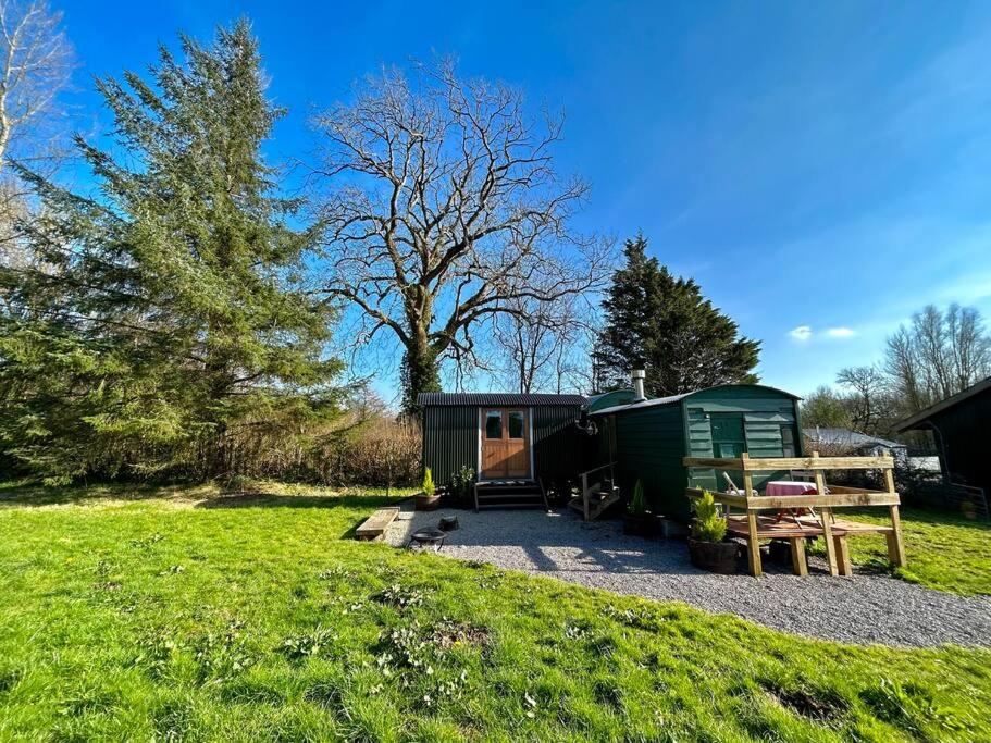 卡迪夫Shepherds Hut in enclosed field的绿色营地,配有桌子和长凳