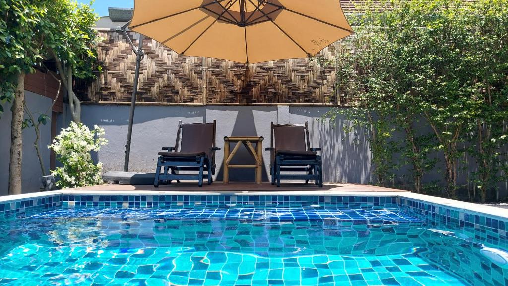 奥南海滩唐雅私人泳池别墅的一个带两把椅子和遮阳伞的游泳池