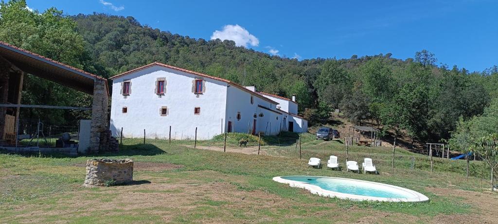 巴塞罗那Mas Can Puig de Fuirosos的一座农场,在一座建筑旁边的草地上设有一个游泳池