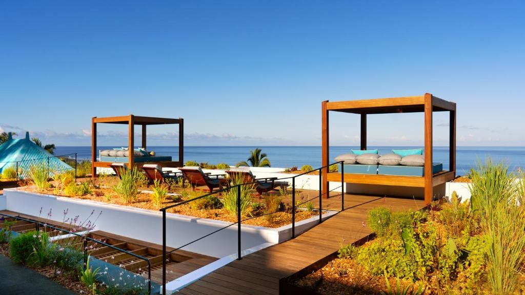 圣勒蓝色马古拉特海景酒店 - 罗莱夏朵精品酒店集团的一个带花园的甲板,花园内配有床和椅子