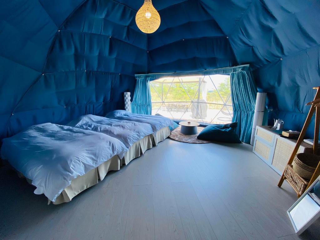 藏王chillout glamping zao的蓝色的客房设有两张床和窗户。