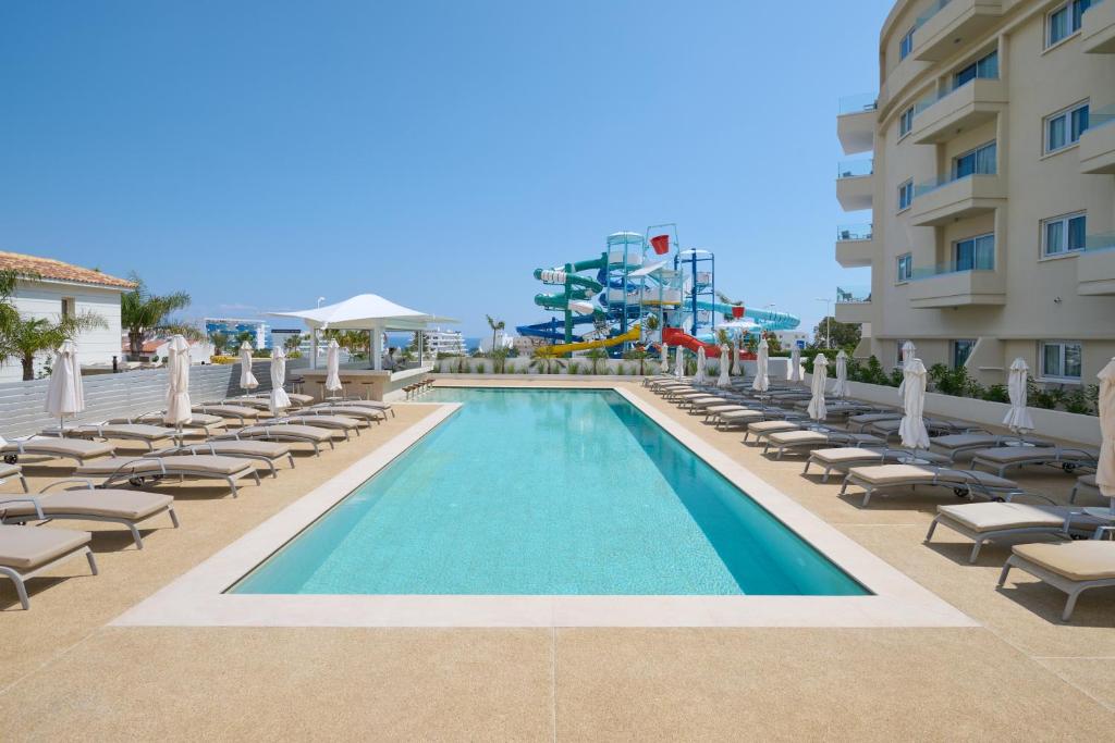 普罗塔拉斯Sunrise Oasis Hotel & Waterpark的一个带躺椅的游泳池和一间酒店