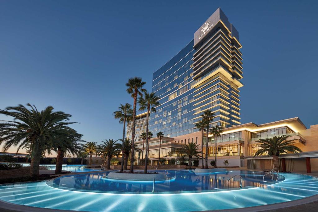 珀斯皇冠塔珀斯酒店的一座棕榈树环绕的大建筑,位于游泳池前