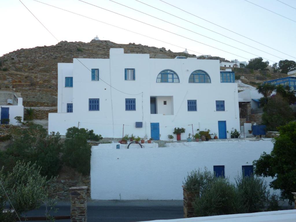 伊奥斯乔拉Vasilis Place Ιos的白色的房子,有蓝色的窗户和山丘