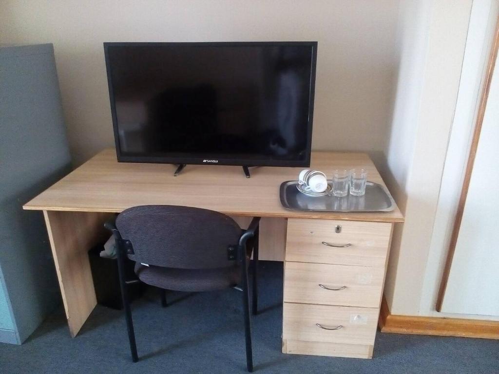 哈拉雷Neat guest suite with office corner - 2101的一张桌子,电视机和椅子放在房间里