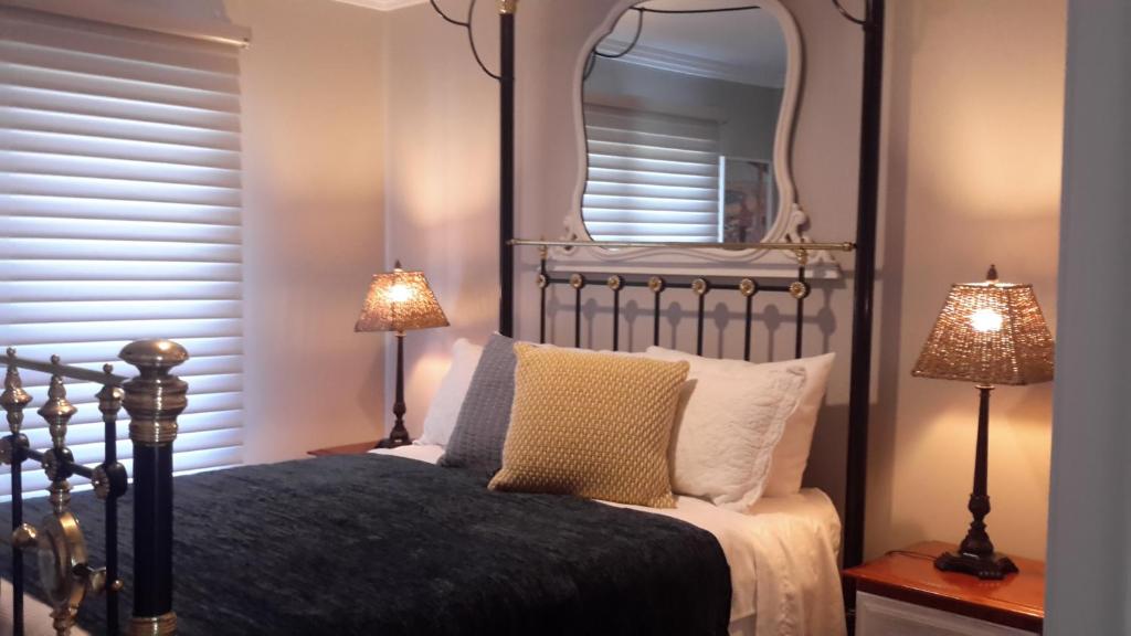 Camden Valley Terrace 4的一间卧室配有一张带镜子的床和两盏灯。