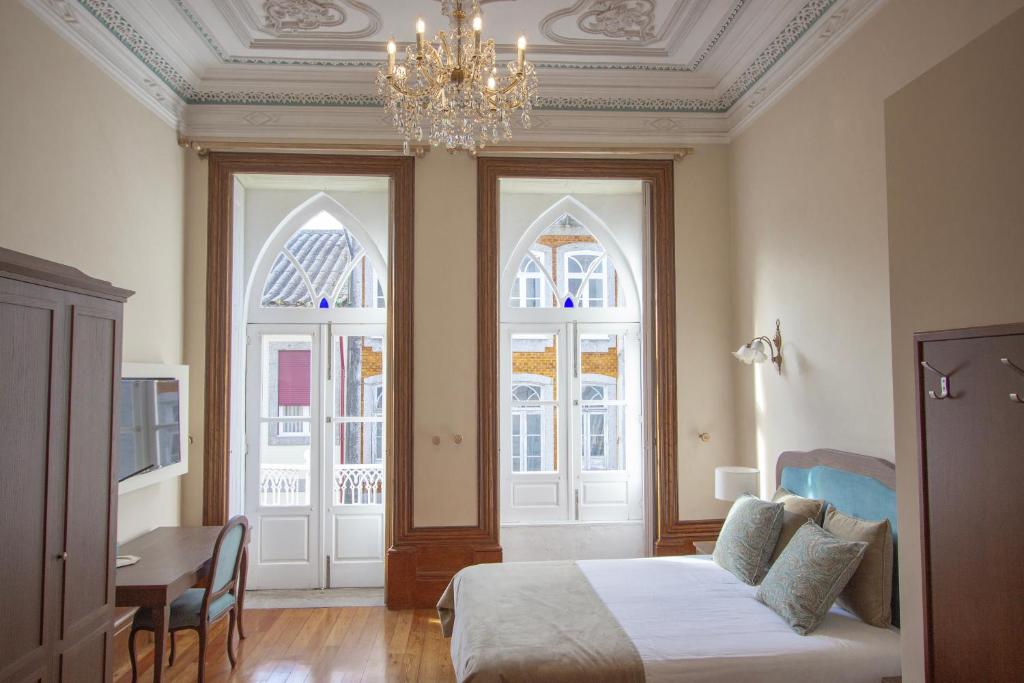 吉马良斯Dom José Alojamentos by Guestify的一间卧室配有一张床、一个吊灯和两个窗户。