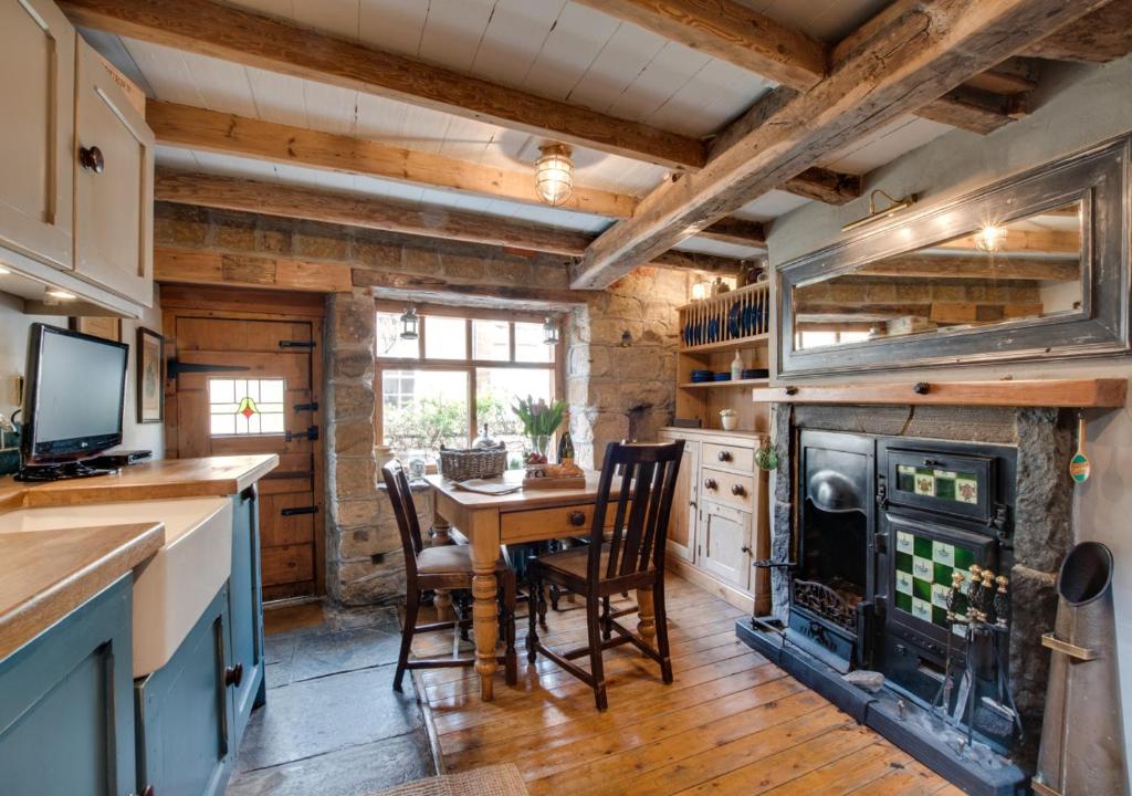 罗宾胡兹贝Green Cottage的厨房配有桌椅和壁炉。