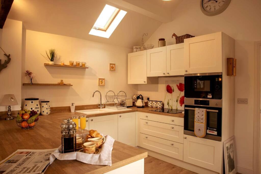 The Coach House - Raskelf - YO61 3LD的厨房配有白色橱柜和台面