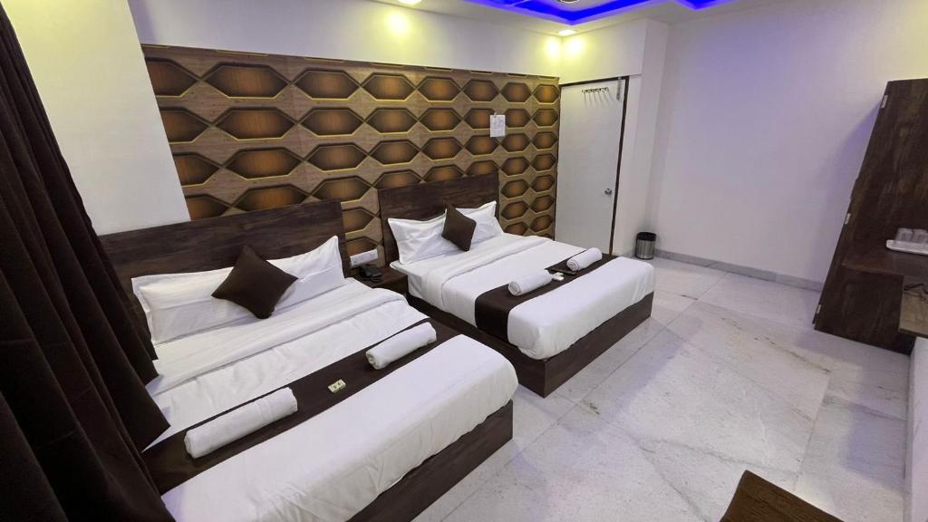 孟买Hotel Plaza Rooms - Prabhadevi Dadar的一间卧室设有两张床和一堵墙