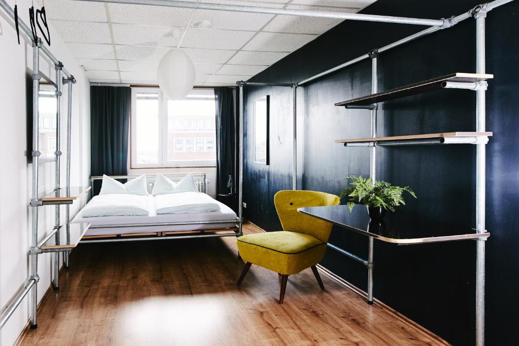 明斯特Sleep Station Hostel的一间卧室配有一张床和一张黄色椅子