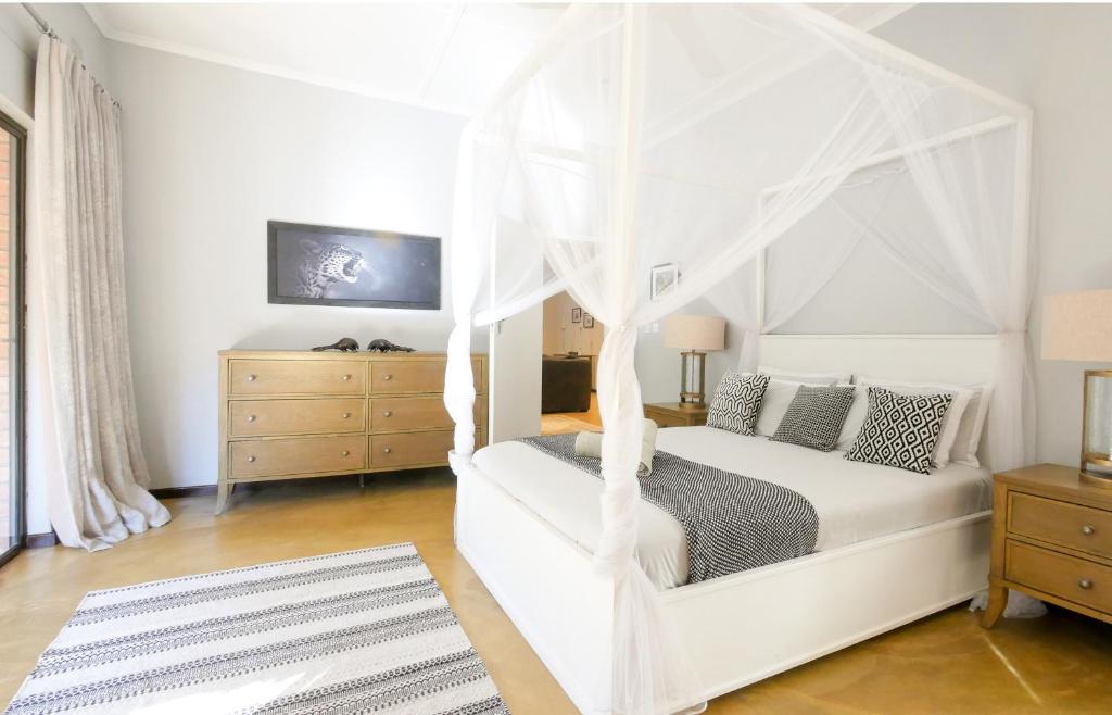 维多利亚瀑布Victoria Falls Holiday Home的一间卧室配有一张带天蓬的白色床