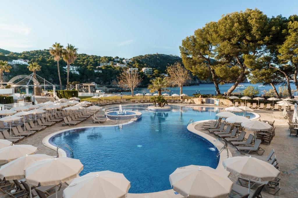 坎普德玛Alua Gran Camp de Mar的一个带白色遮阳伞和桌椅的游泳池