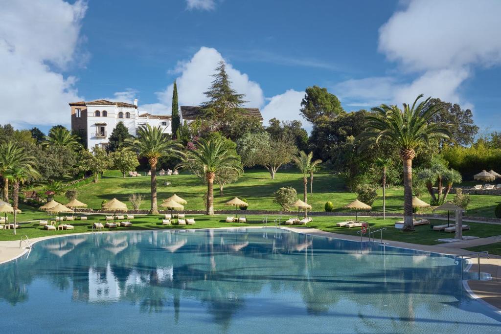 维拉努埃瓦·德·塔皮亚La Bobadilla, a Royal Hideaway Hotel的棕榈树游泳池和背景建筑