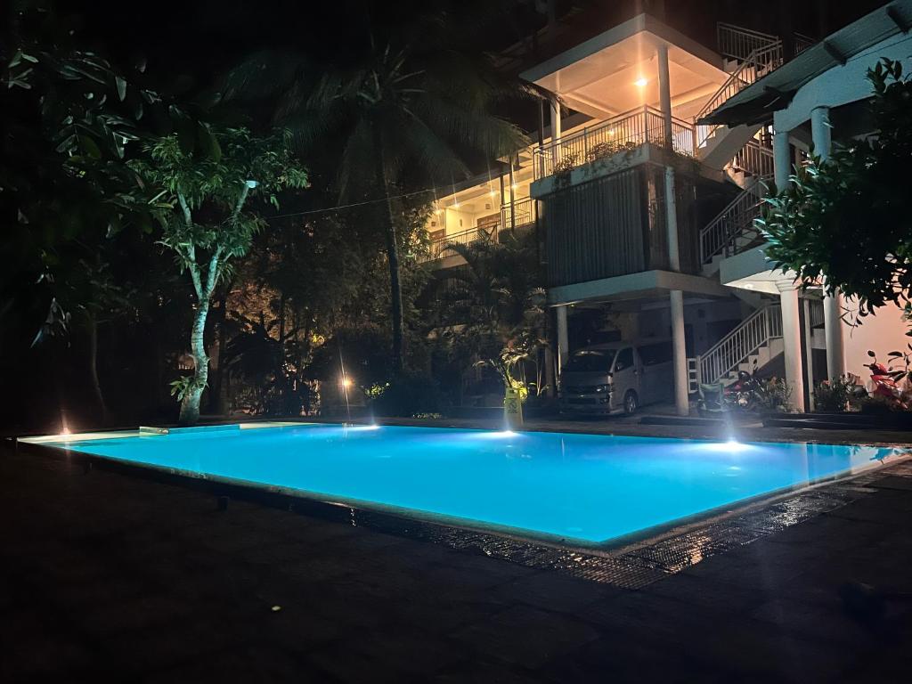 康提French Garden Kandy的一座大型蓝色游泳池,在晚上在大楼前