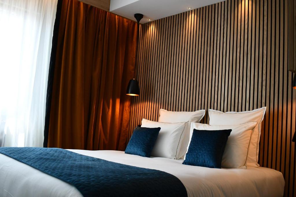 吉福蒙尚波贝尔Le Cheval Blanc - Lac du Der - Logis Hotel的一间卧室配有一张带蓝白色枕头的大床