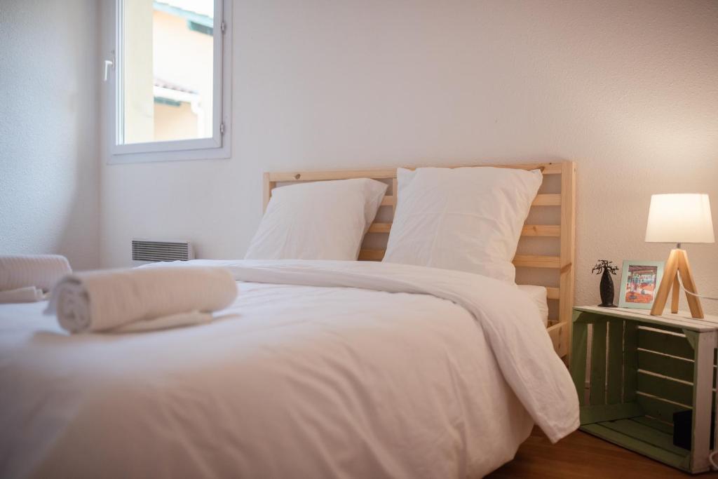卡布勒通Duplex familial proche plage et commerces的一间卧室配有一张带白色床单的床和一扇窗户。