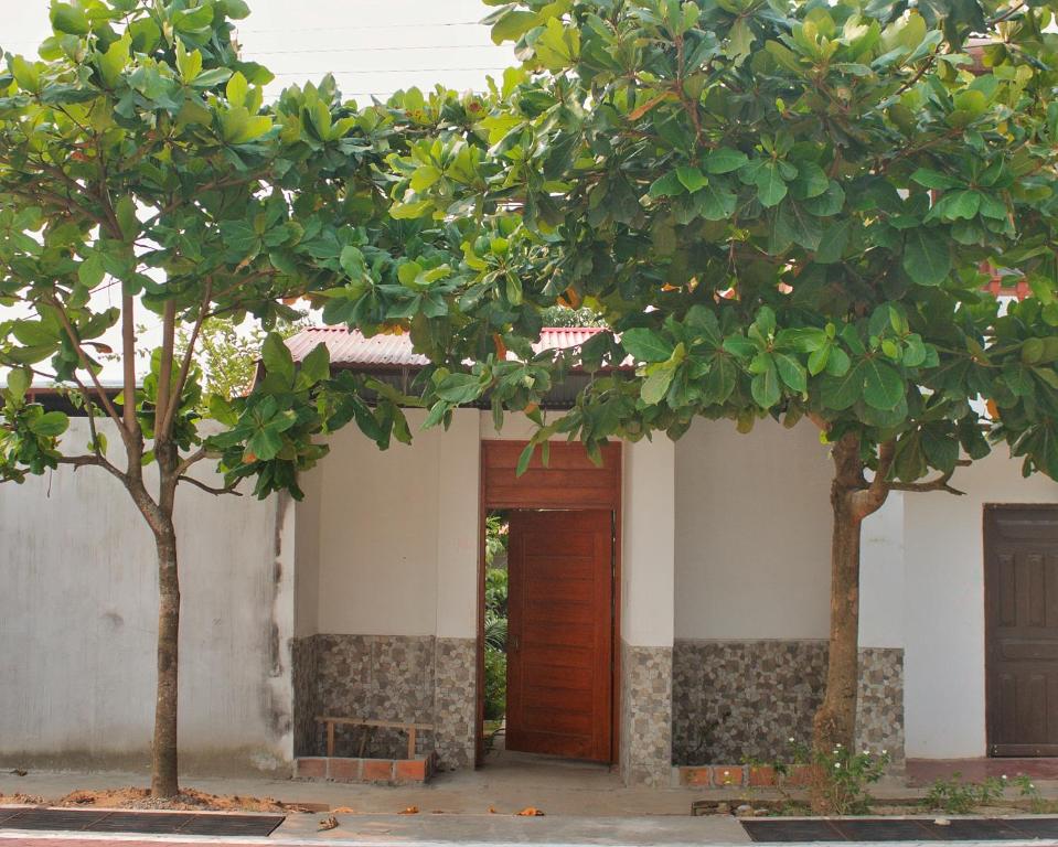 YurimaguasCasa Albina的一座带木门和两棵树的建筑