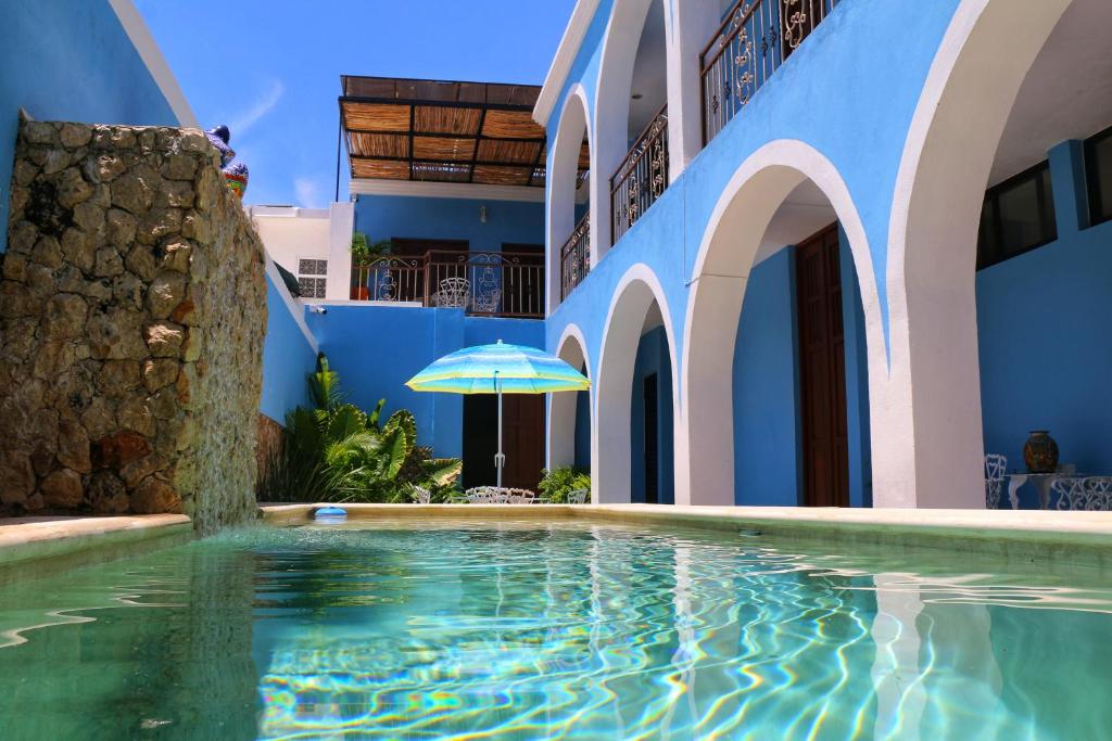 梅里达Boutique Casa Azuli Santiago的一座带遮阳伞的建筑前的游泳池