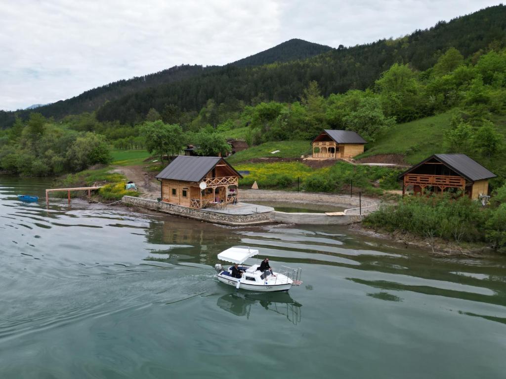 Kuće sa bazenom Višegrad Drina的一群房子旁边的水中的小船