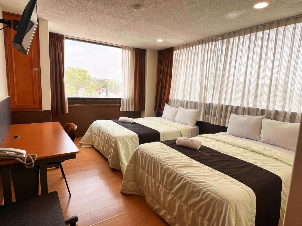 普埃布拉Puebla Inn Express的酒店客房设有两张床、一张书桌和一个窗户。