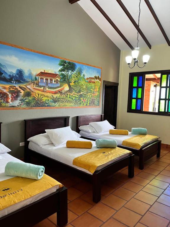 金巴亚Hotel Campestre Los Mangos的一间设有三张床的客房,墙上挂着一幅画