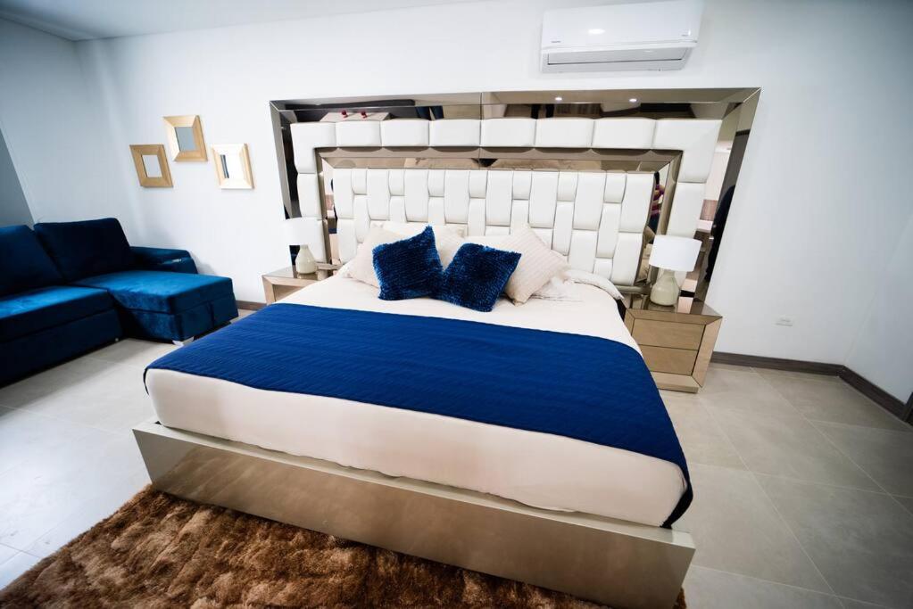 luxury suite presidencial的一间卧室配有一张大床和一张蓝色的沙发