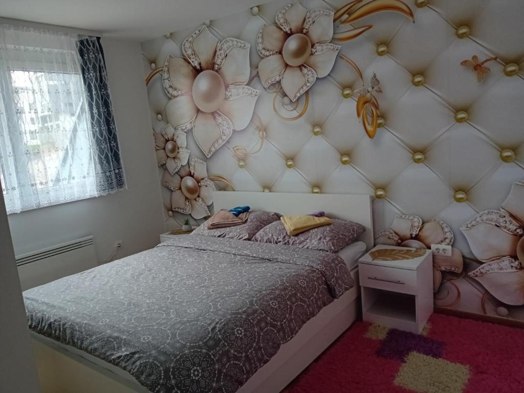 别拉什尼察Apartman "AROMA 1"Bjelasnica的一间卧室设有一张床和花墙