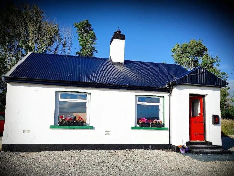 Mary Grays Hideaway 2 Bedroom Irish Cottage的白色的房子,设有两个窗户和红色的门