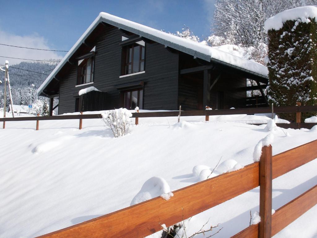 VagneyLes Chalets Du Pres D'amont的雪覆盖的房屋,设有木栅栏
