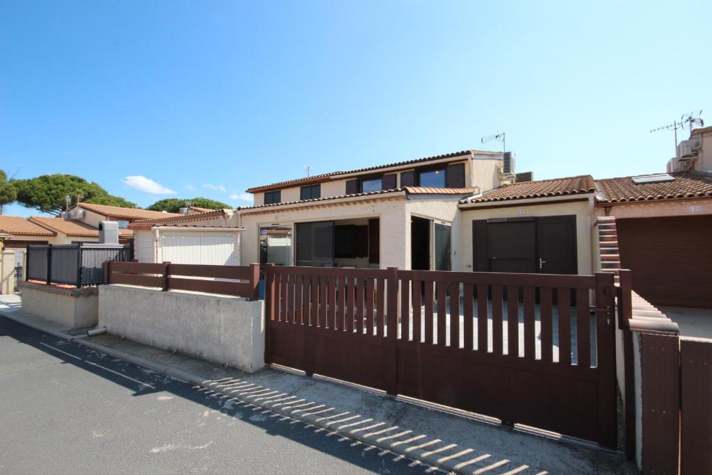 波尔蒂拉盖Villa climatisée, 4 couchages, 2 chambres, véranda, Résidence LES TAMARIS, accès payant pour les piscines, wifi, PORTIRAGNES PLAGE LRTAML9的一排带木栅栏的房屋